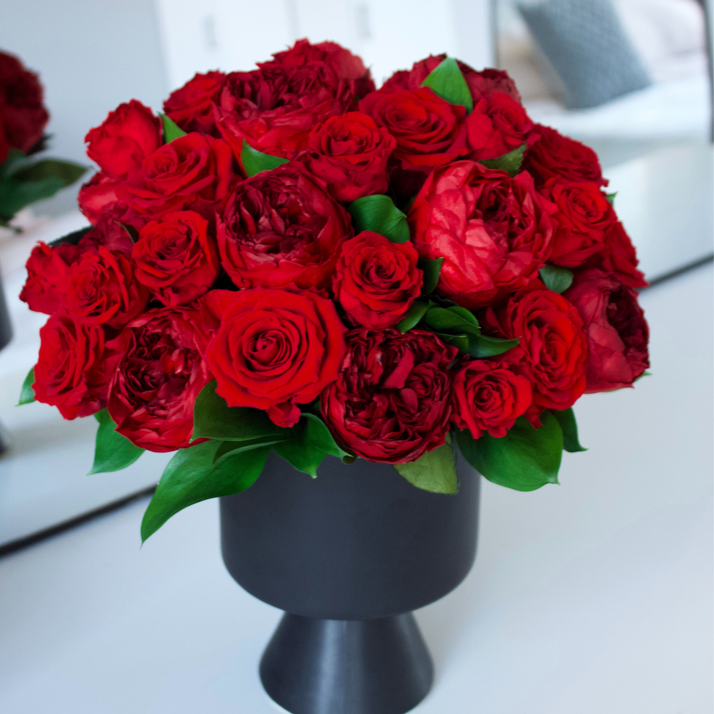 The Sybarite by Eos Blooms: a black vase with preserved roses and green leaves.