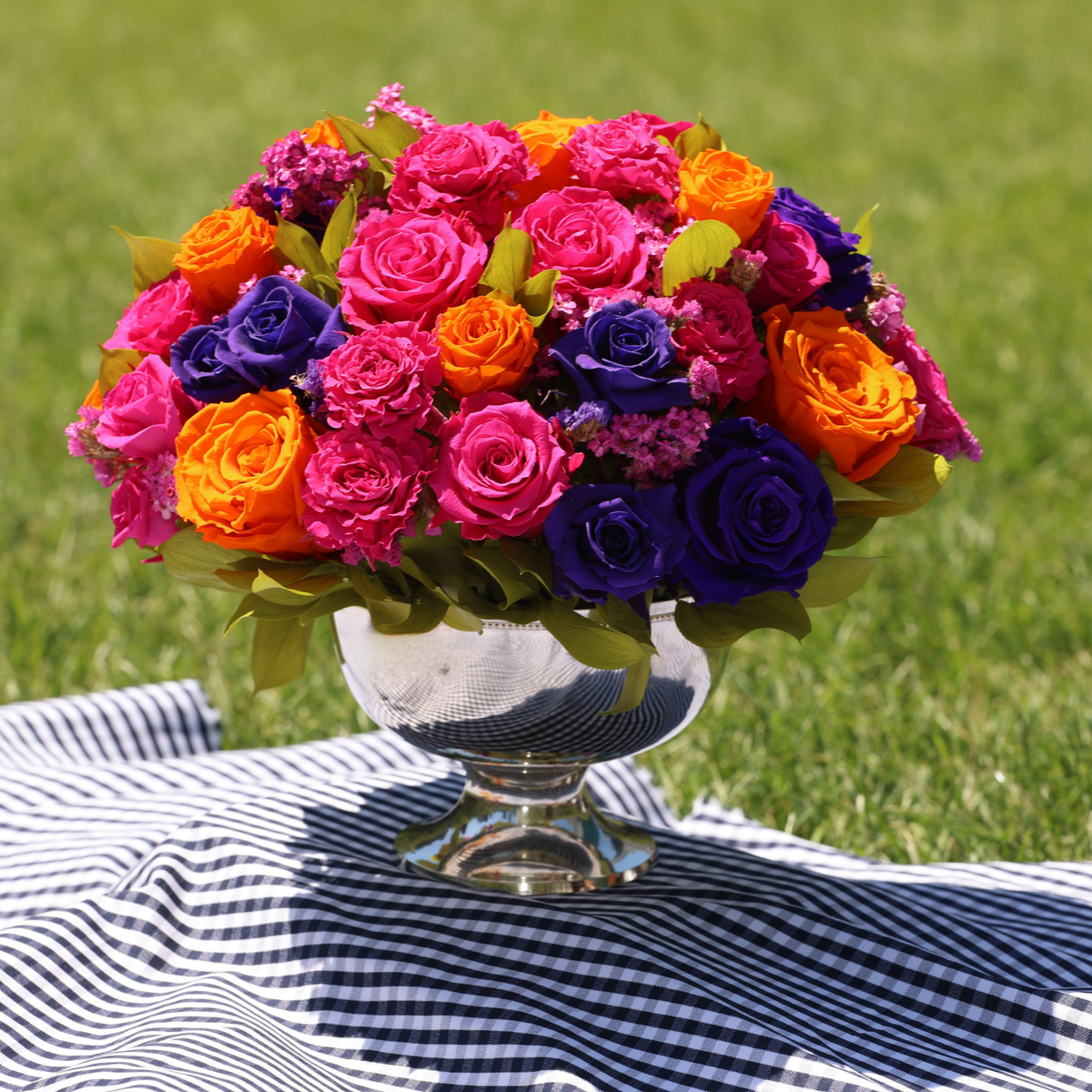 The Mariposa by Eos Blooms sits on a striped cloth on grass.