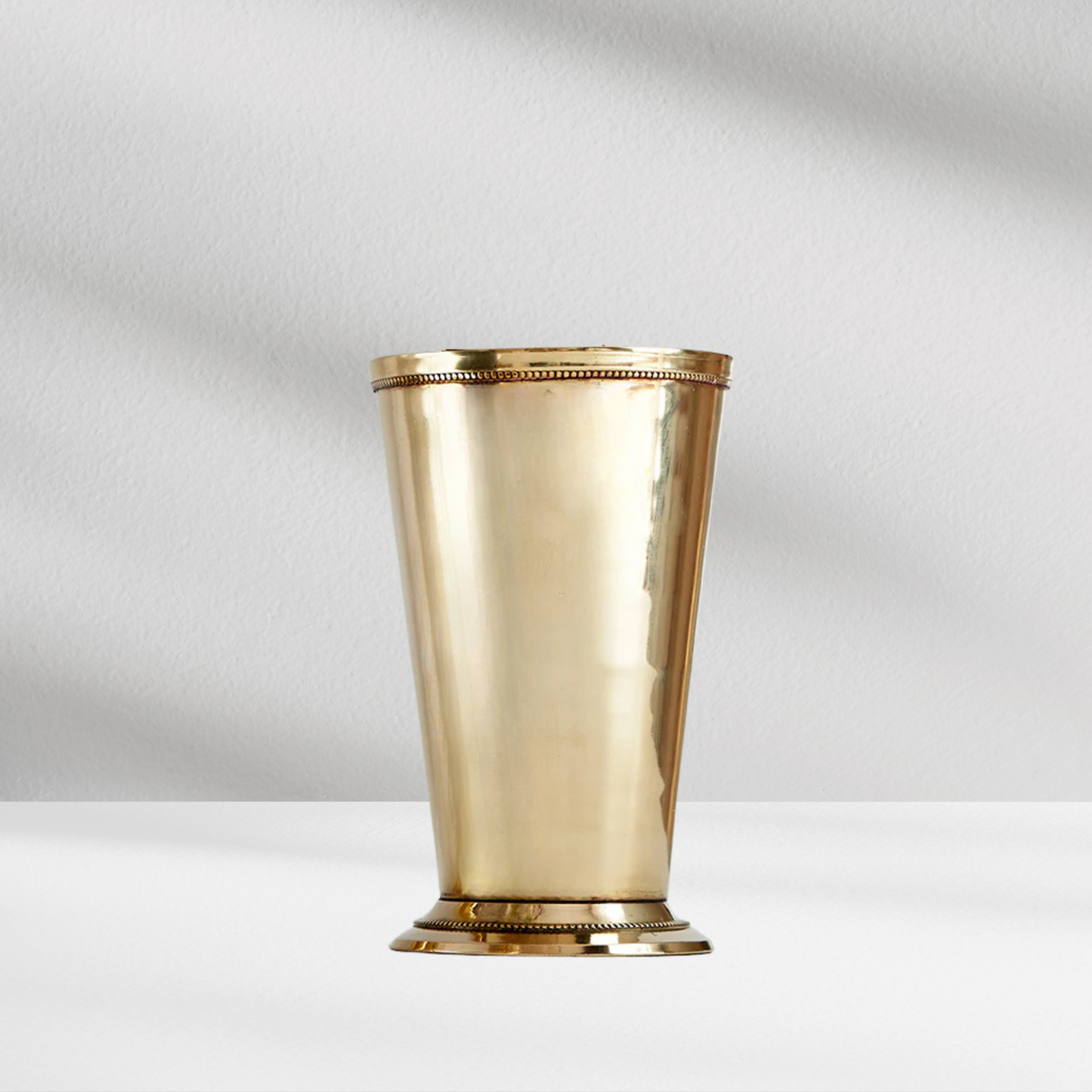 A tall, shiny brass Charleston Vase by Eos Blooms, inspired by Southern julep cups.