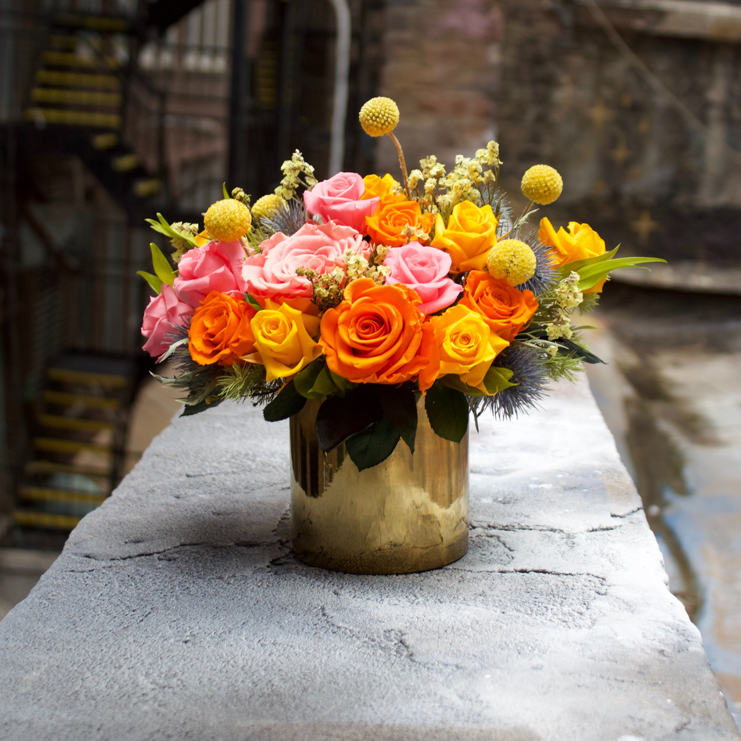 The Remi (Petite) by Eos Blooms: a vibrant bi-color rose bouquet in a gold vase.