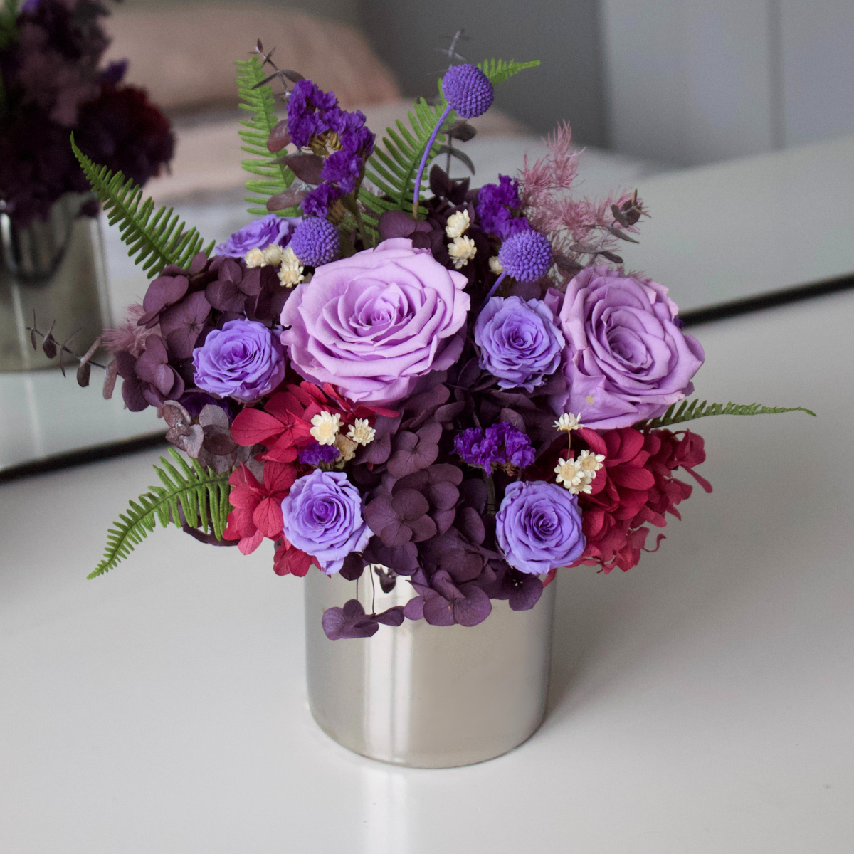 Ultraviolet (Petite) by Eos Blooms: purple roses and ferns in a silver vase.