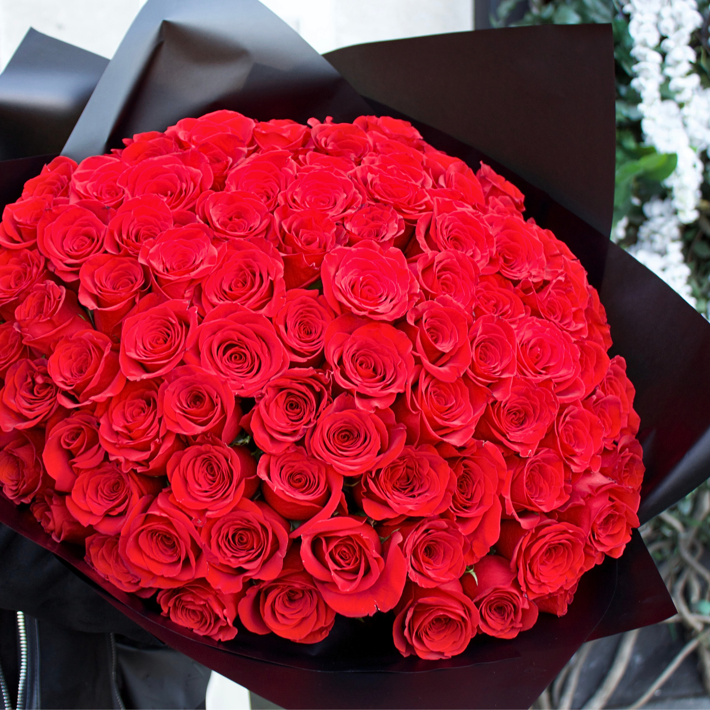 The Hundred by Eos Blooms: 100 vibrant Ecuadorian red roses wrapped in elegant black paper.