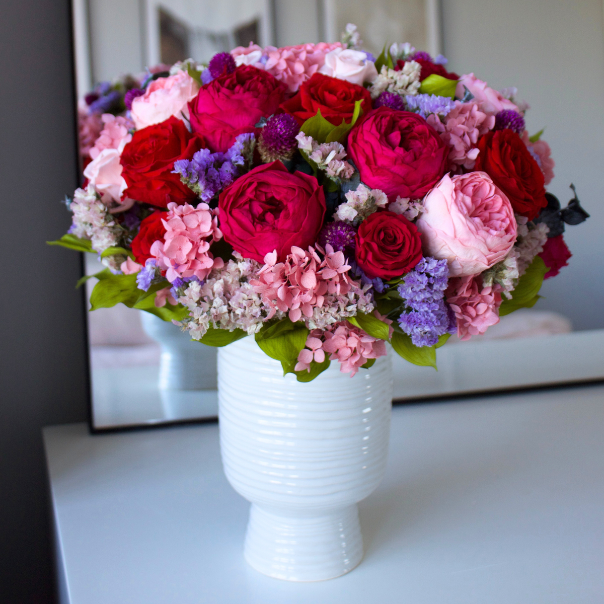 Eos Blooms' Ma Chérie: red, pink & purple preserved flowers in a white vase on a table.