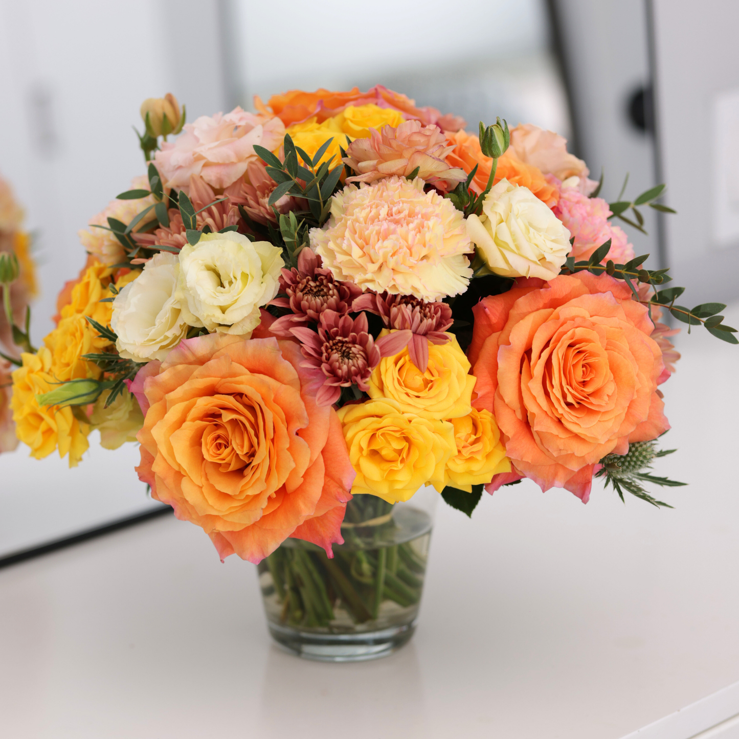 The Sunburst | Hotel Guest by Eos Blooms: honey-yellow roses & cream flowers in a glass vase.