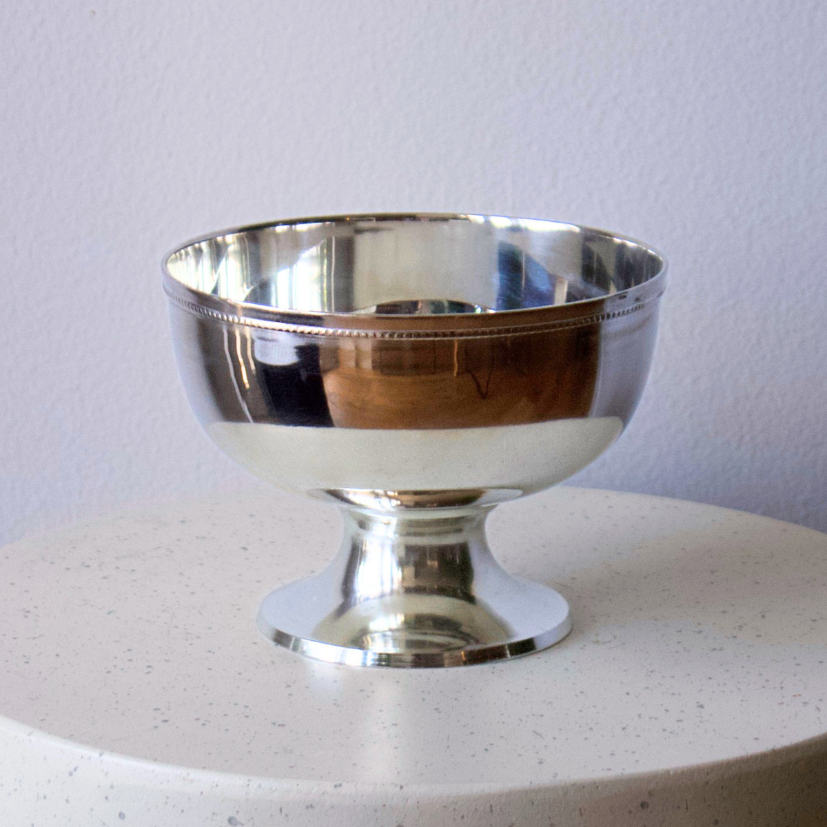 Eos Blooms Silver Pedestal bowl shines on a light surface, ideal as a table centrepiece.