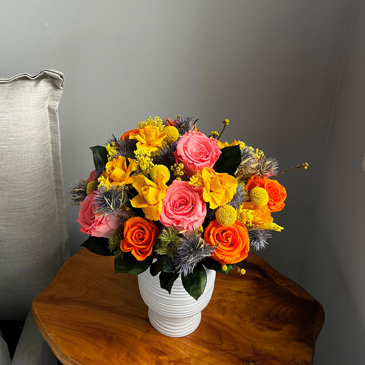 The Remi by Eos Blooms: a vibrant pink, orange, and yellow bouquet in a white vase.