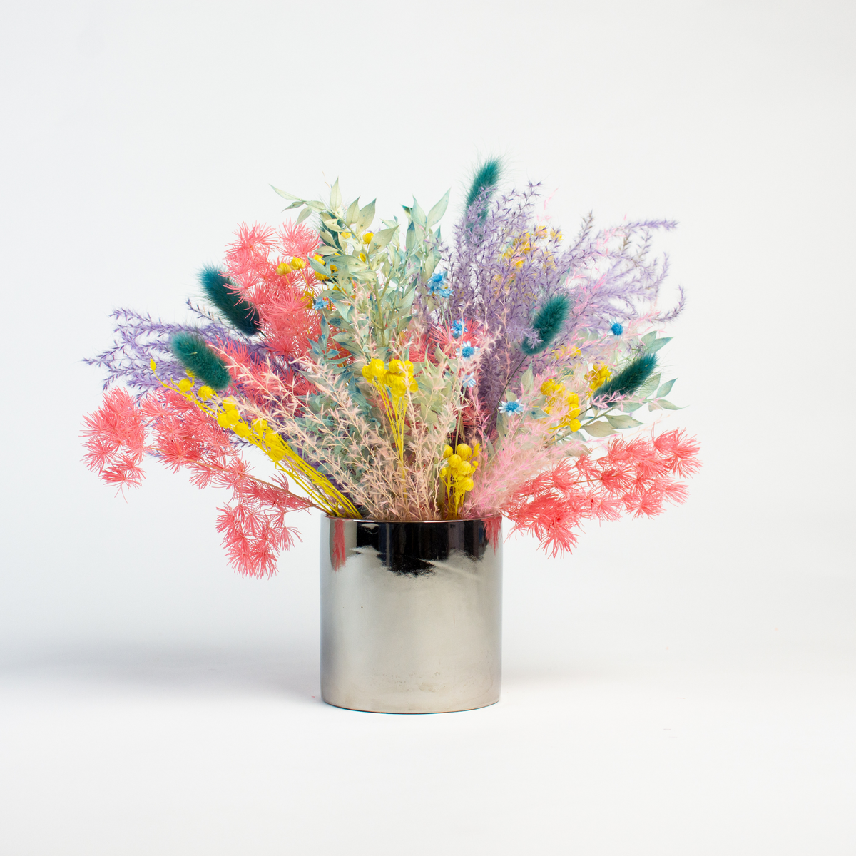 Prism by Eos Blooms: colorful preserved flowers in a shiny silver vase on white background.