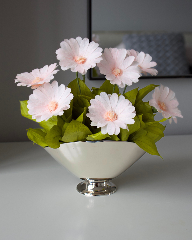 The Margarita by Eos Blooms: preserved daisies in silver vase, light pink blooms, green leaves.