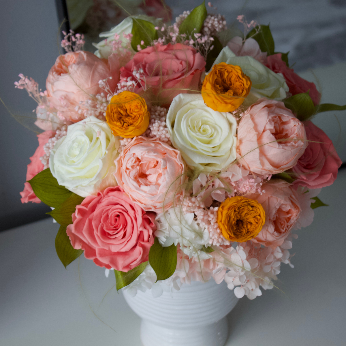 The Glimmer by Eos Blooms: preserved pink, white, and yellow roses in a white vase.
