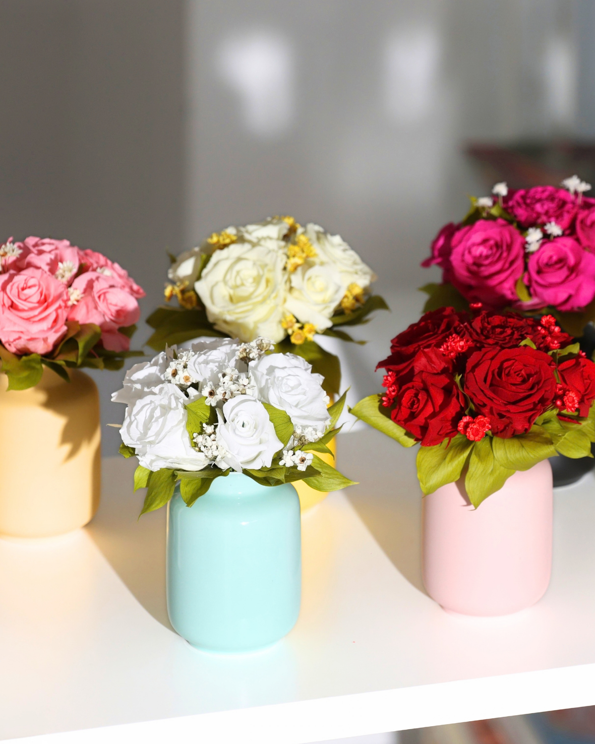 Five Eos Blooms Mini Milk Jars with colorful preserved flowers displayed on a white surface.