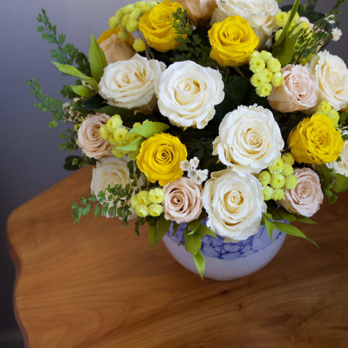 The Amalfi by Eos Blooms: preserved white, yellow & pale pink roses in a blue vase.