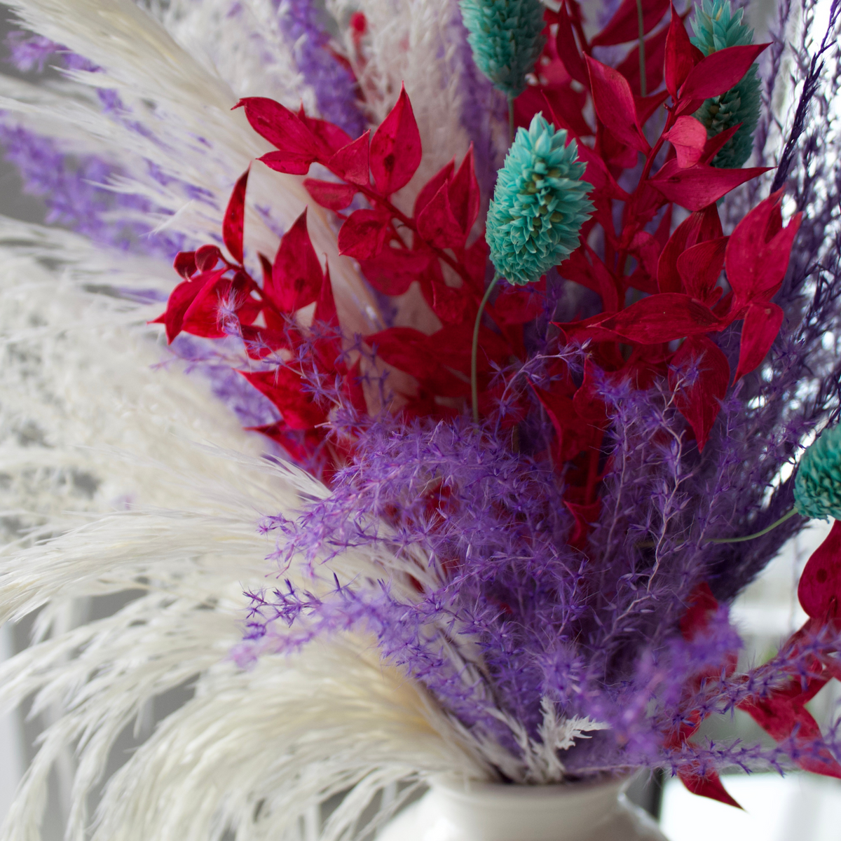 Confetti Burst by Eos Blooms: preserved flowers in a vase with red, purple, white & teal stems.