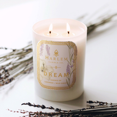 White candle labeled Dream with lavender sprigs around it, two wicks burning.
