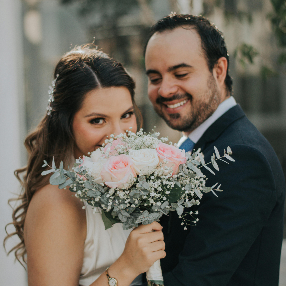 The bride holds "The Promise" bouquet by Eos Blooms as she smiles with the groom.