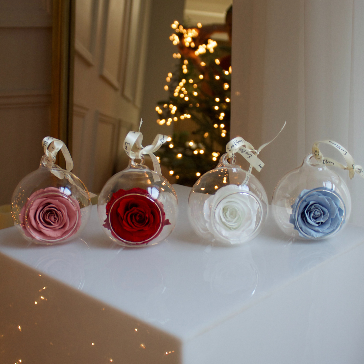 Eos Blooms Glass Ornaments 4-Pack: everlasting blooms shine before a lit Christmas tree.
