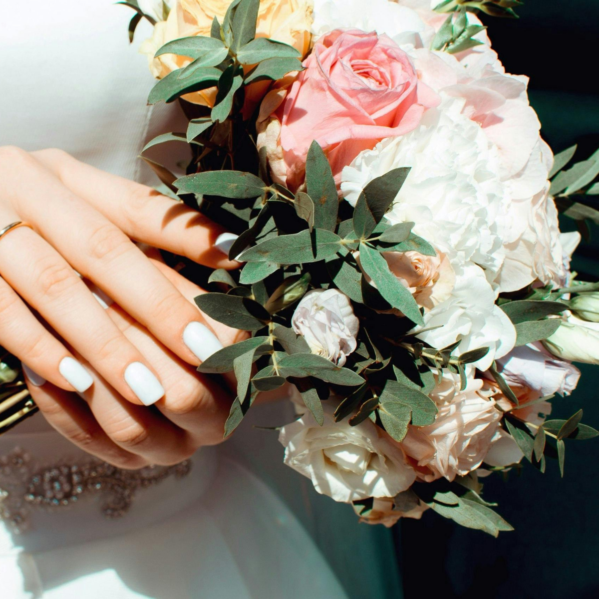 Bride holding "The Promise" bouquet by Eos Blooms, displaying her ring and manicured nails.