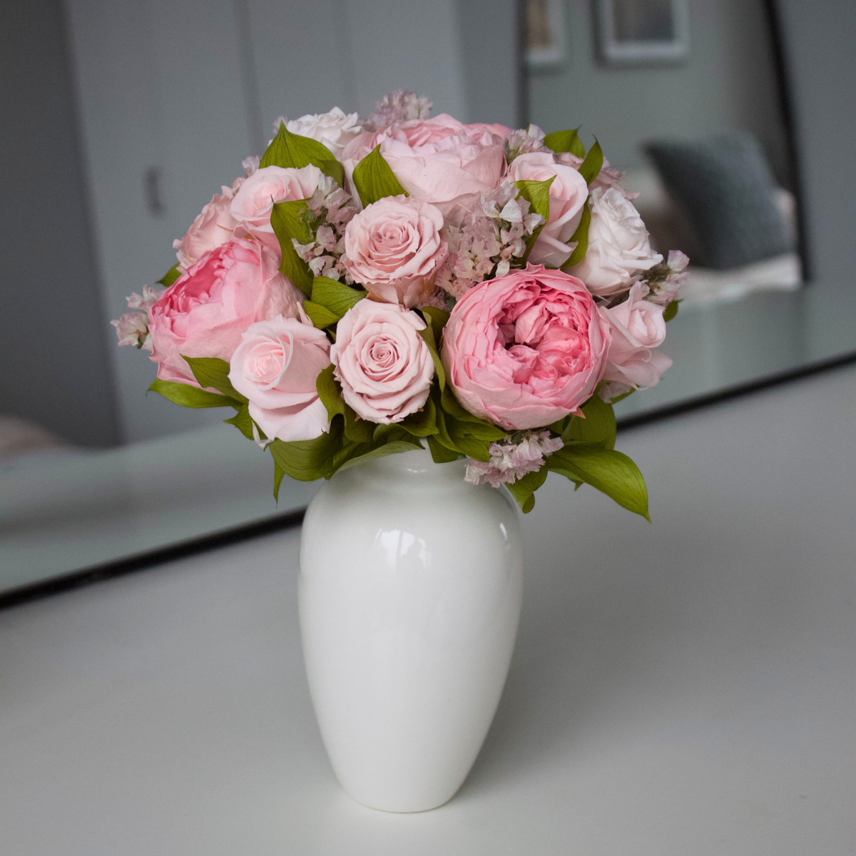The Paloma (Petite) by Eos Blooms: a white vase with preserved roses and green leaves.