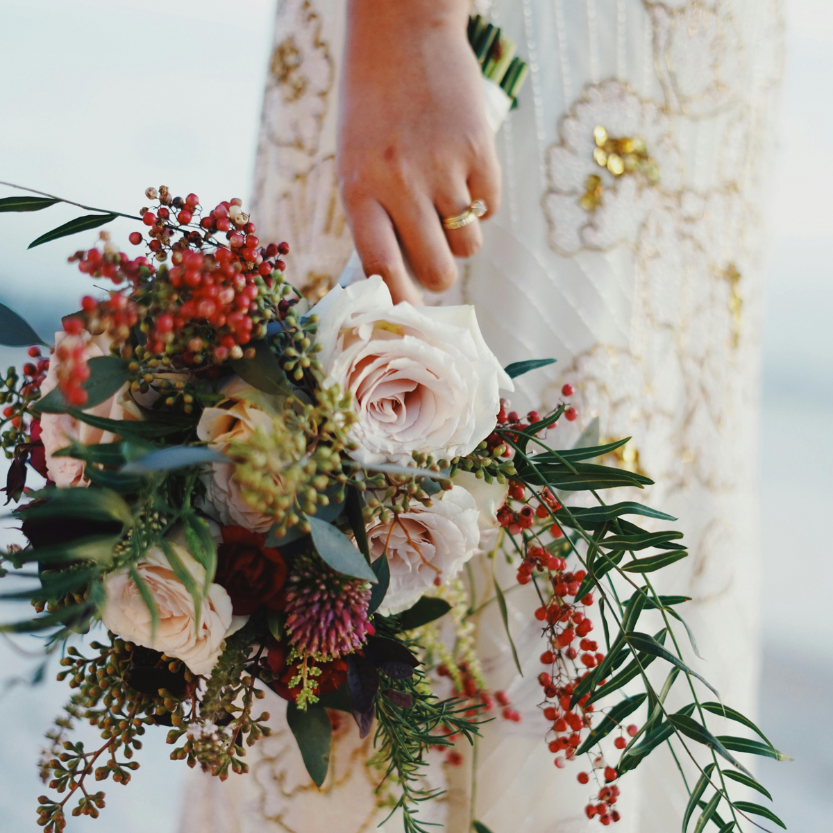 Bride holding "The Promise" bouquet by Eos Blooms, wearing a white dress.