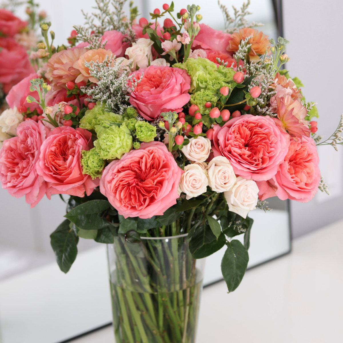 The Bon Bon by Eos Blooms features candy-pink roses and greenery in a glass vase.