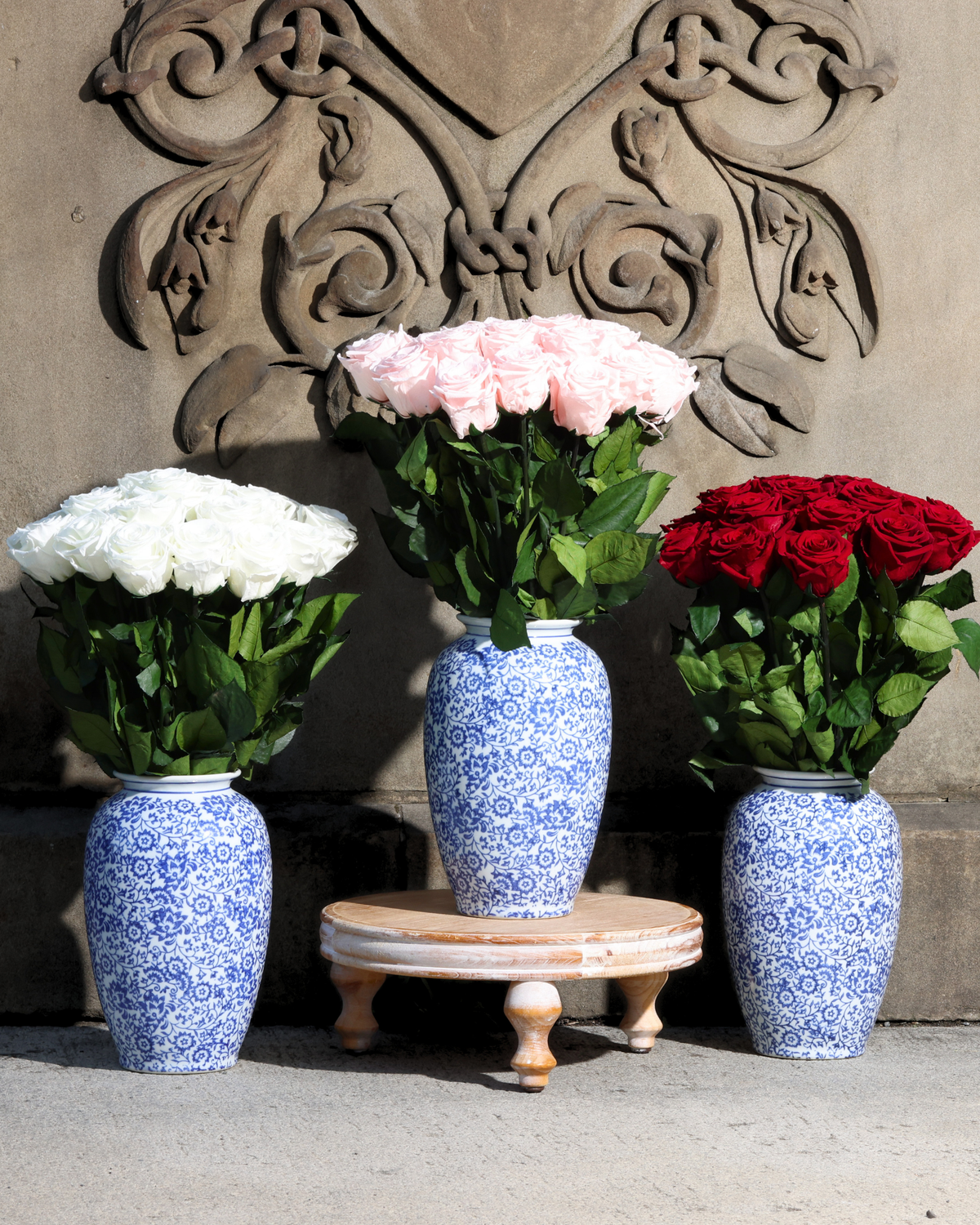 The Amalia preserved roses by Eos Blooms, displayed before an ornate stone wall.