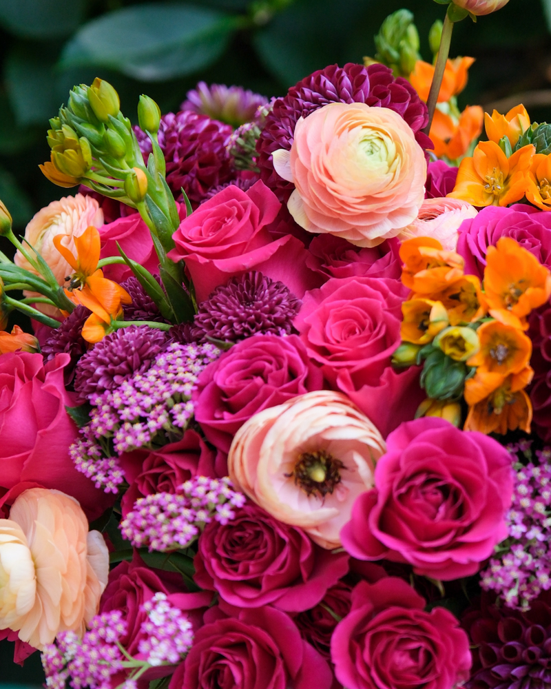 The Leo ♌ by Eos Blooms: pink roses, orange blooms & ranunculus with lush green leaves.