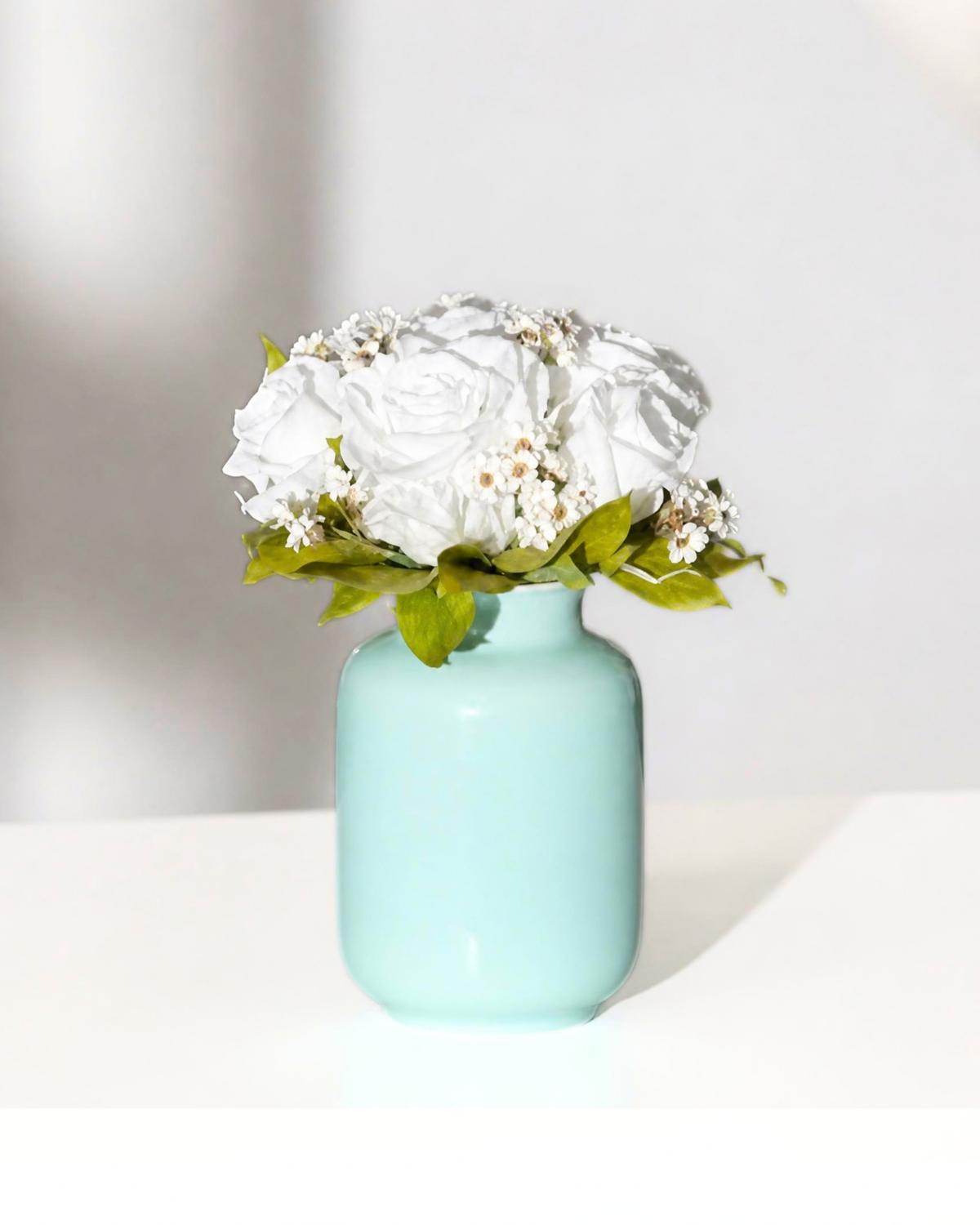 Eos Blooms Mini Milk Jars: white preserved flowers with green leaves in a ceramic jar.