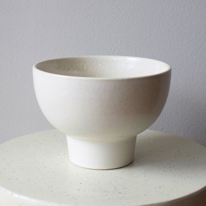 The Eos Blooms White Ceramic Pedestal (Medium) rests on a round, light-colored surface.