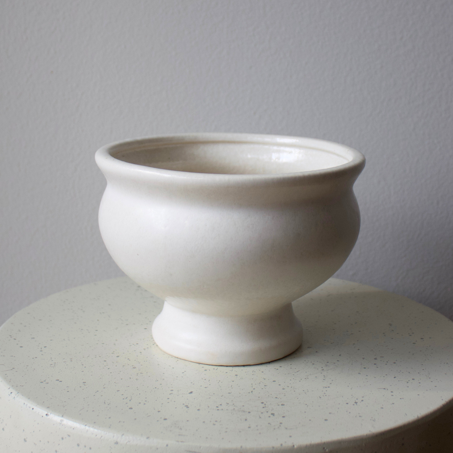 A matte cream ceramic vase sits on the Eos Blooms Toledo Pedestal against a plain background.