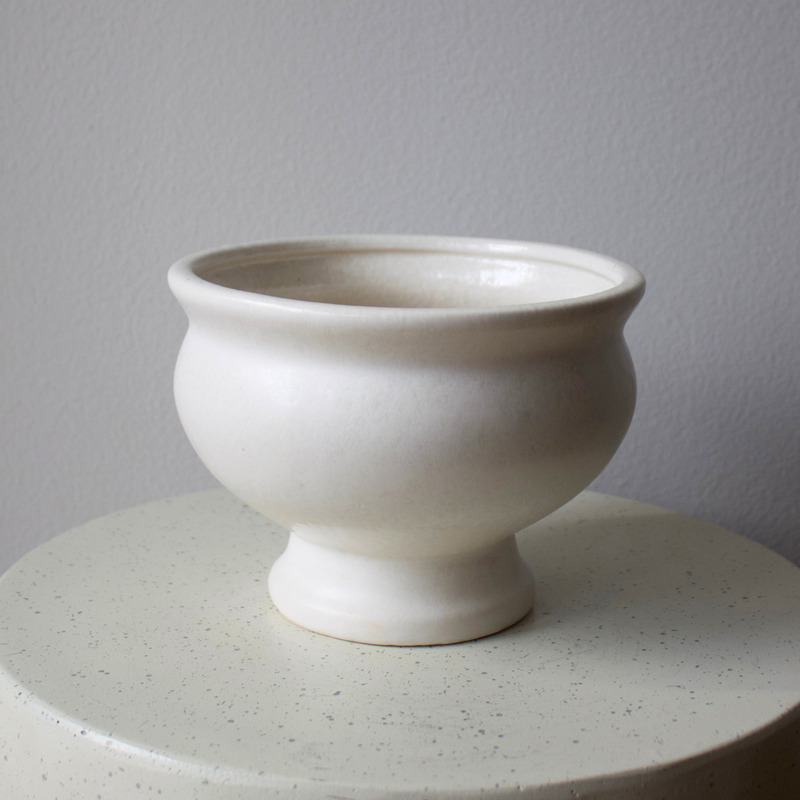 A matte cream ceramic vase sits on the Eos Blooms Toledo Pedestal against a plain background.