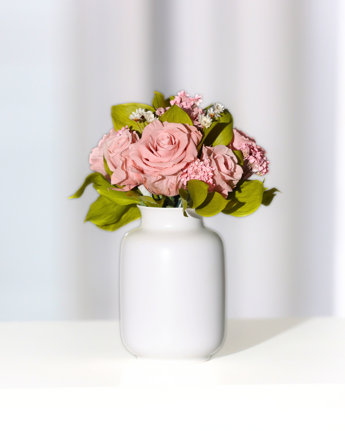 Eos Blooms Mini Milk Jars: pink preserved flowers & green leaves in a ceramic milk jar.