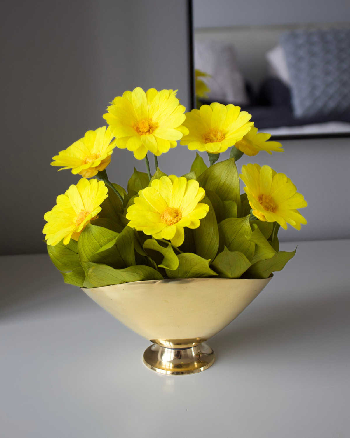 The Margarita by Eos Blooms: preserved daisies in a gold vase with green leaves.