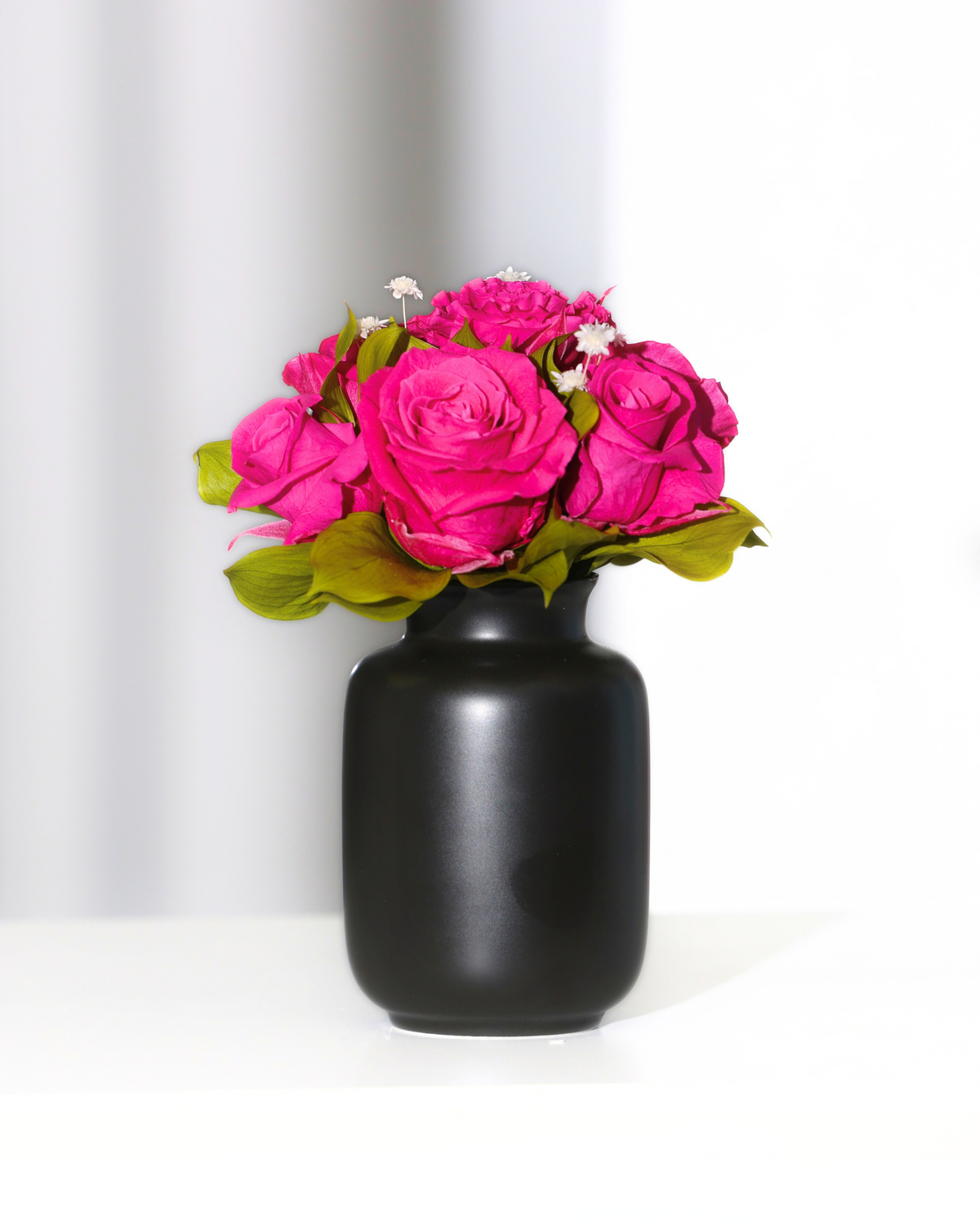 Mini Milk Jars by Eos Blooms with pink roses on a white surface and white background.