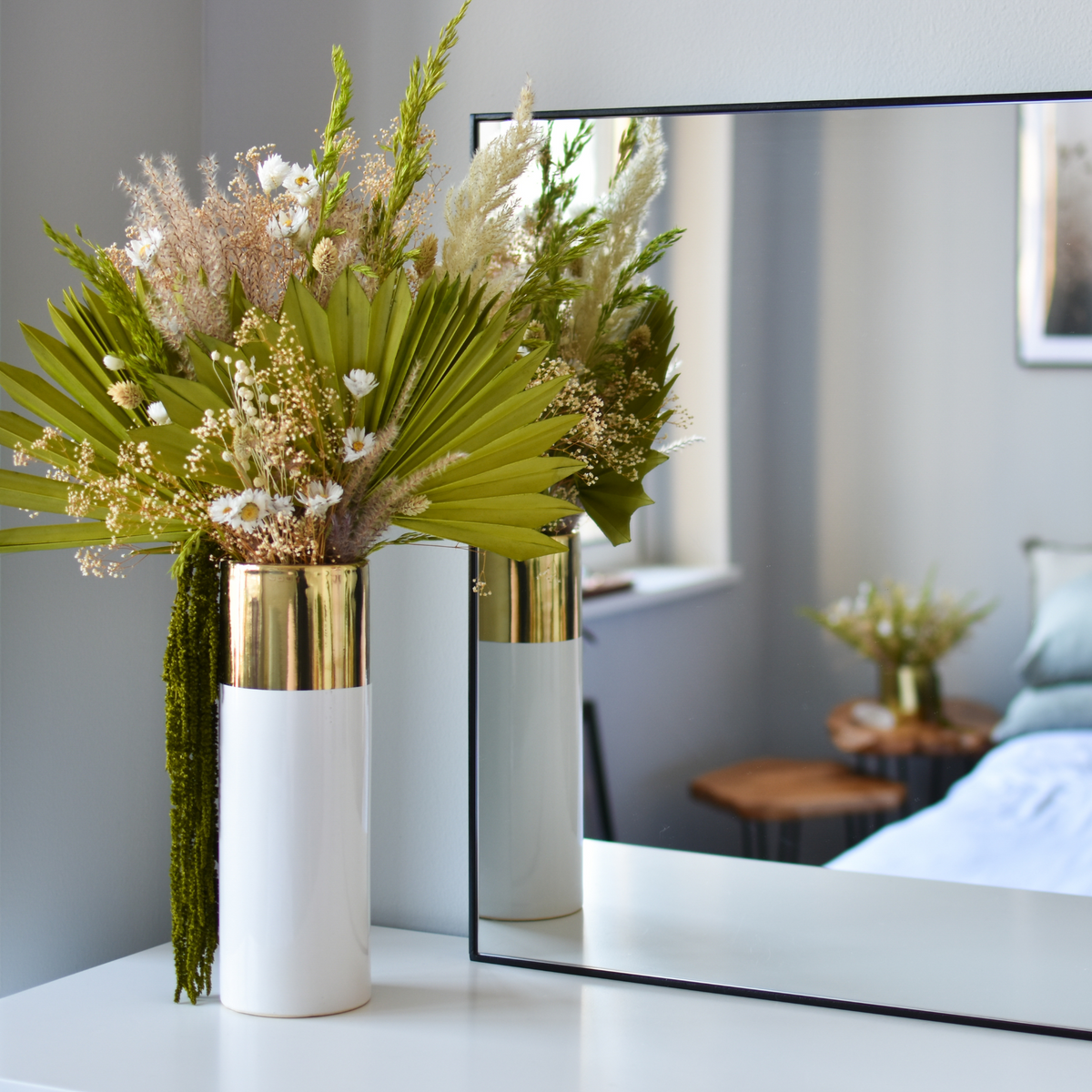 A Preserved Flower Subscription by Eos Blooms adorns a white table before a mirror.
