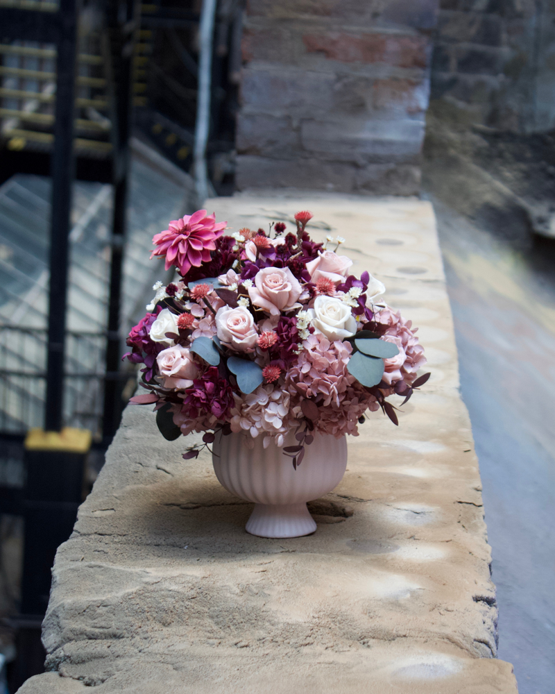 The Mulberry (Petite) by Eos Blooms in a vase on a ledge, city view behind.
