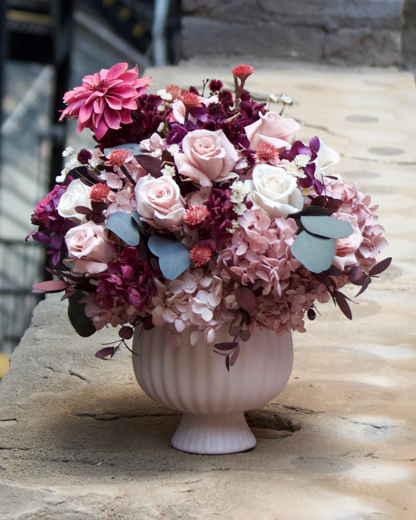 The Mulberry (Petite) by Eos Blooms—pink & purple flowers in a white vase on a stone ledge.