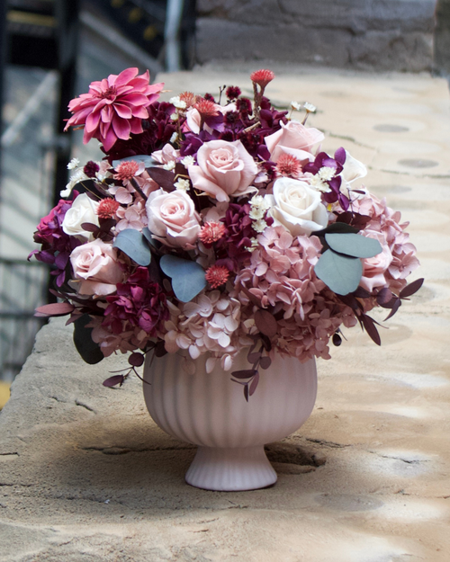The Mulberry (Petite) by Eos Blooms—pink & purple flowers in a white vase on a stone ledge.