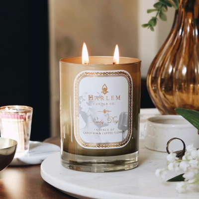 A lit Harlem Candle Co. candle on a marble tray with decorative items nearby.