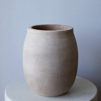The Alexandria Vase by Eos Blooms adds rustic charm, displayed on a round white surface.