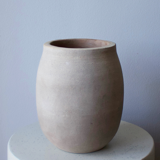The Alexandria Vase by Eos Blooms adds rustic charm, displayed on a round white surface.