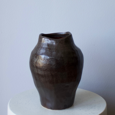 The Eos Blooms Angkor Vase with a wavy rim sits on a white, round surface.