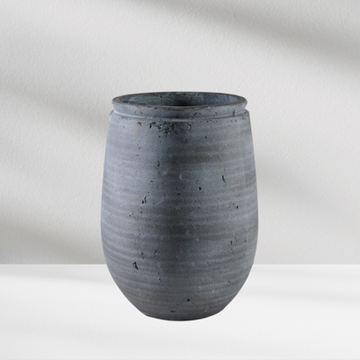 The Eos Blooms Carthage Vase in stone gray sits on a white surface with subtle shadows.