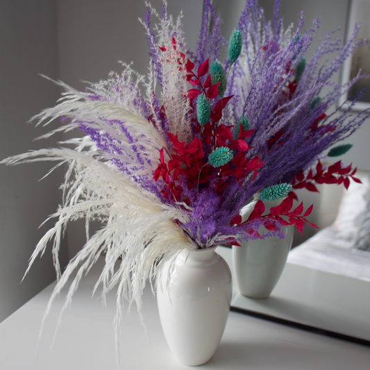 Eos Blooms Confetti Burst vase with preserved flowers and cream, teal, and red accents by mirror.