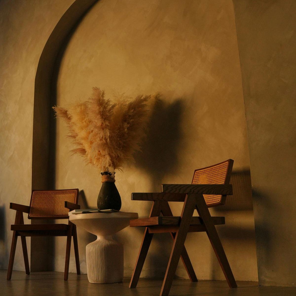 Two wooden chairs, a white table, and Eos Blooms Preserved XL Pampas—elegant home decor.