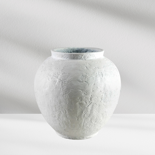 The Santorini Vase by Eos Blooms is a round, textured white ceramic piece on a white surface.