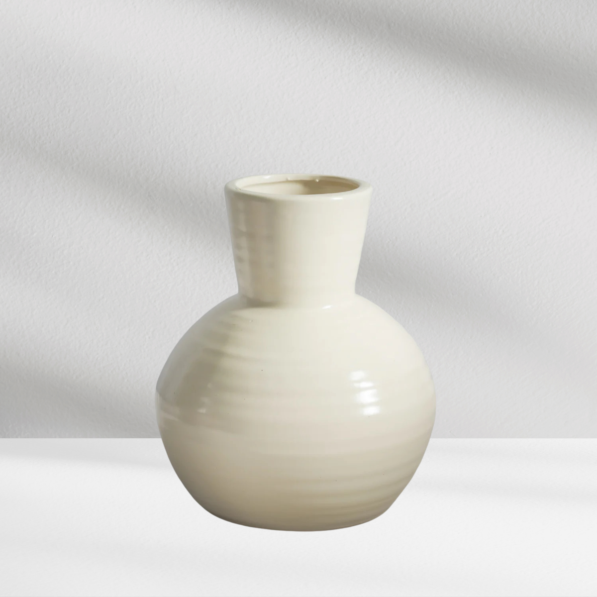 Seoul Vase by Eos Blooms: cream modern vase with round body, narrow neck, on white surface.