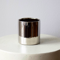 Eos Blooms Silver Cylinder vase on white textured surface with light gray wall backdrop.