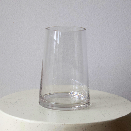 Eos Blooms Tapered Glass Vase displayed upside down on a round, white, speckled surface.
