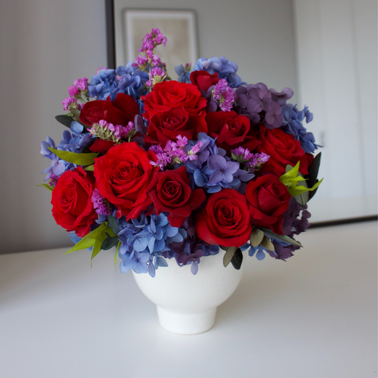 The Bijoux (Petite) by Eos Blooms: a white vase with Forever Roses on a table.