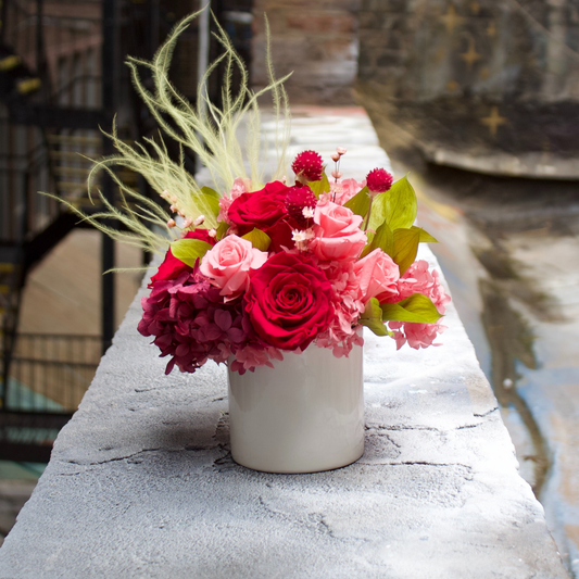 The Cherry On Top by Eos Blooms sits on a concrete ledge outdoors.