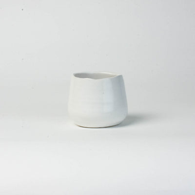 A small, white Eos Blooms ceramic vase on a plain white background.